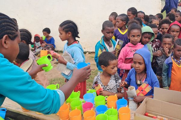Schoolchildren in Tigray, Ethiopia, eat biscuits and tea provided by Mary's Meals. Copyright Mary's Meals