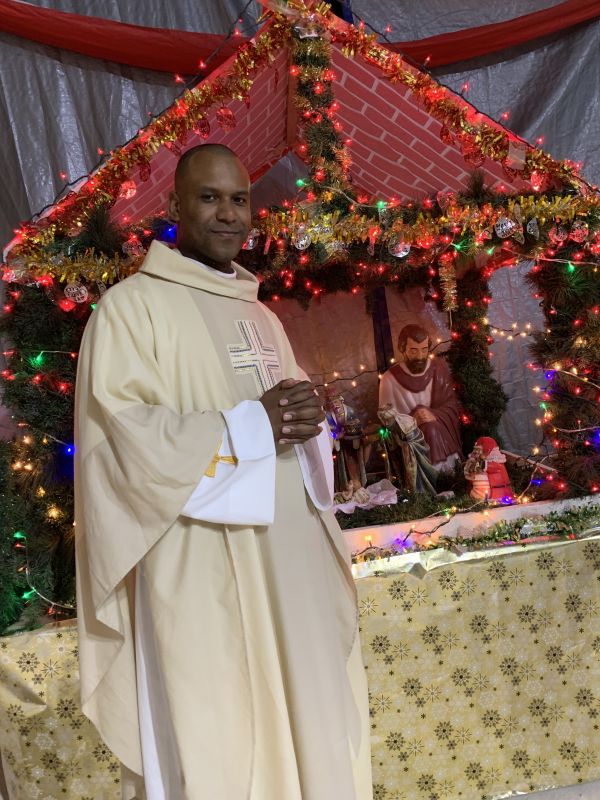 Father Louis Merosne stands before the creche in his "makeshift cathedral" since the main church was too damaged in the 2021 earthquake to be used. Credit: Father Louis Merosne