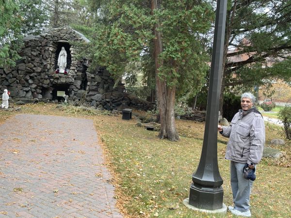 Patrick Norton stands beside the lamp post he was painting near the Marian grotto when he saw a woman in full Benedict habit who he believes was Sister Annella Zervas, OSB. Credit: Patti Armstrong