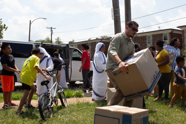 Perpetual Pilgrim Patrick Fayad lifts a heavy "Blessing Box" full of donations, assisting the Missionaries of Charity as they distribute the boxes to refugee families. The sisters frequently come to this apartment complex to offer assistance to the families and faith instruction to the children. Credit: Jonah McKeown/CNA