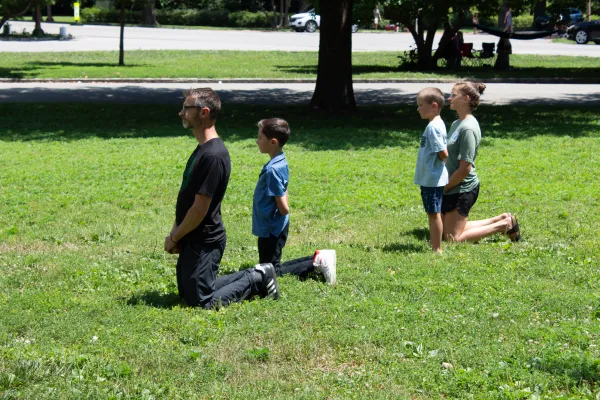 A family kneels as the Eucharist makes its way through Tower Grove Park. Credit: Jonah McKeown/CNA