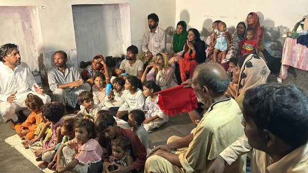 A local volunteer (left in photo) speaks to an extended family of Pakistani Christians liberated&nbsp;from slavery. Credit: Courtesy of Order of St. Elijah