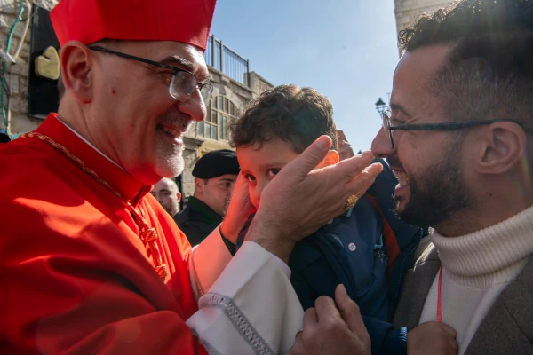 Cardinal Pierbattista Pizzaballa, Latin patriarch of Jerusalem, stops to greet some faithful and bless a child during his arrival in Bethlehem for the Christmas celebrations on Dec. 24, 2024. Credit: Marinella Bandini