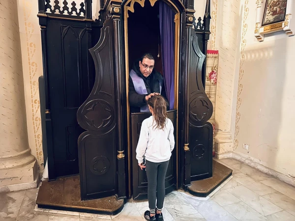 Father Yusuf Asad, one of the priests of the Latin Parish of the Holy Family in Gaza, administers the sacrament of penance to a young girl. Credit: Photo courtesy of Father Gabriel Romanelli
