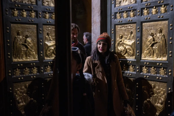 A visitor admires the bronze panels of the Holy Door at St. Peter's Basilica, specially illuminated for the 'White Night' celebration of the Jubilee of Artists, Feb. 16, 2025. Credit: Daniel Ibáñez/CNA