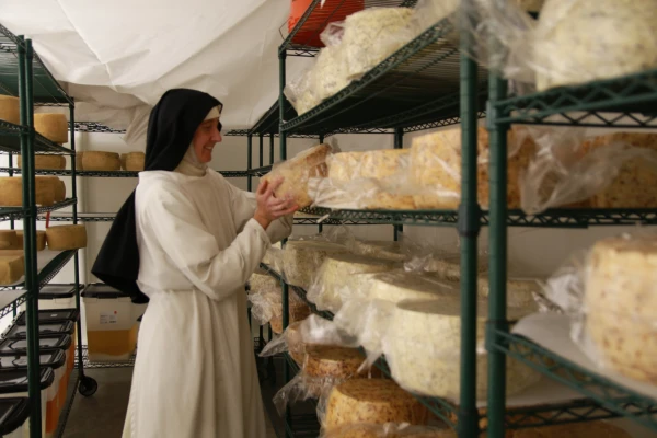 A Norbertine sister tends to the young cheese wheels in the cheese aging room in 2024. Credit: Photo courtesy of the Norbertine Canonesses
