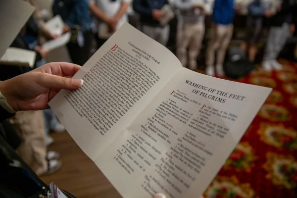 A pilgrim listens to a reading from the Gospel of St. John and follows the Latin prayers in English in Rome, Monday, March 24, 2025. Credit: Hannah Brockhaus/CNA