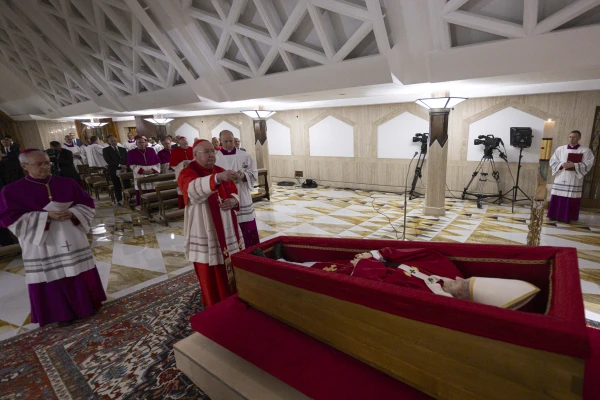 Cardinal Kevin Farrell blesses Pope Francis as he lies in state at the Vatican's Domus Sanctae Marthae before his transfer to St. Peter's Basilica for public veneration, Monday, April 21, 2025. Credit: Vatican Media