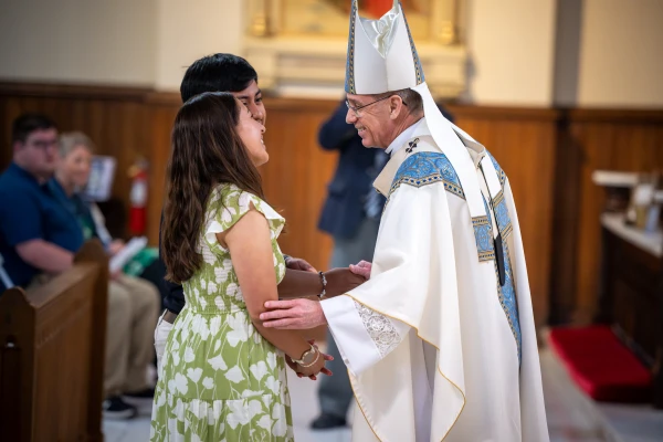 Archbishop Charles C. Thompson greets perpetual pilgrims Leslie Reyes-Hernandez and Johnathan Silvino Hernandez-Jose as they bring up the gifts at the Mass for the St. Katharine Drexel Route of the National Eucharistic Pilgrimage. May 18, 2025. Credit: Jeffrey Bruno