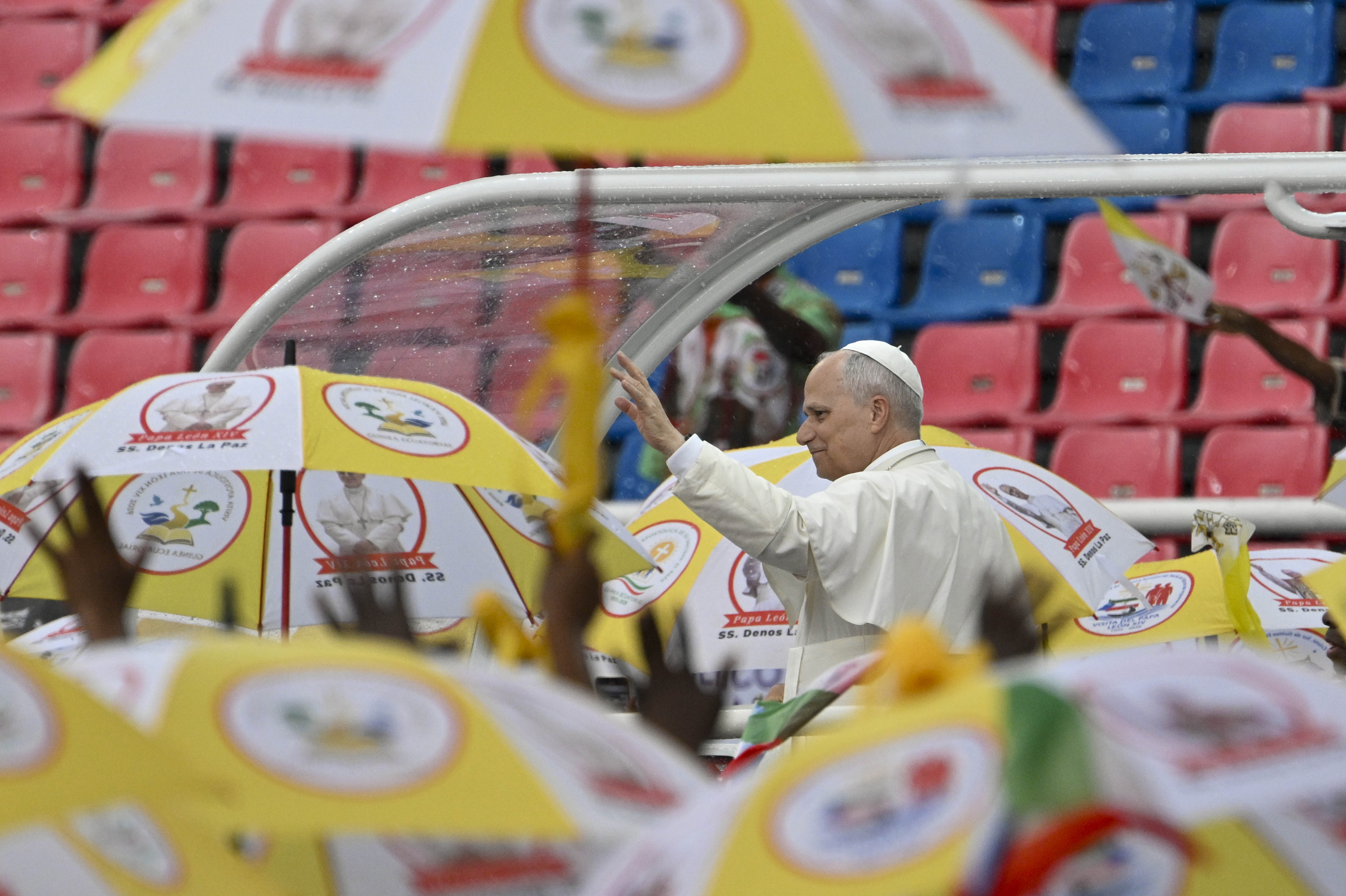 Pope Leo XIV greets a crowd under umbrellas during a meeting with families at Bata Stadium in Equatorial Guinea, Wednesday, April 22, 2026. | Credit: Vatican Media