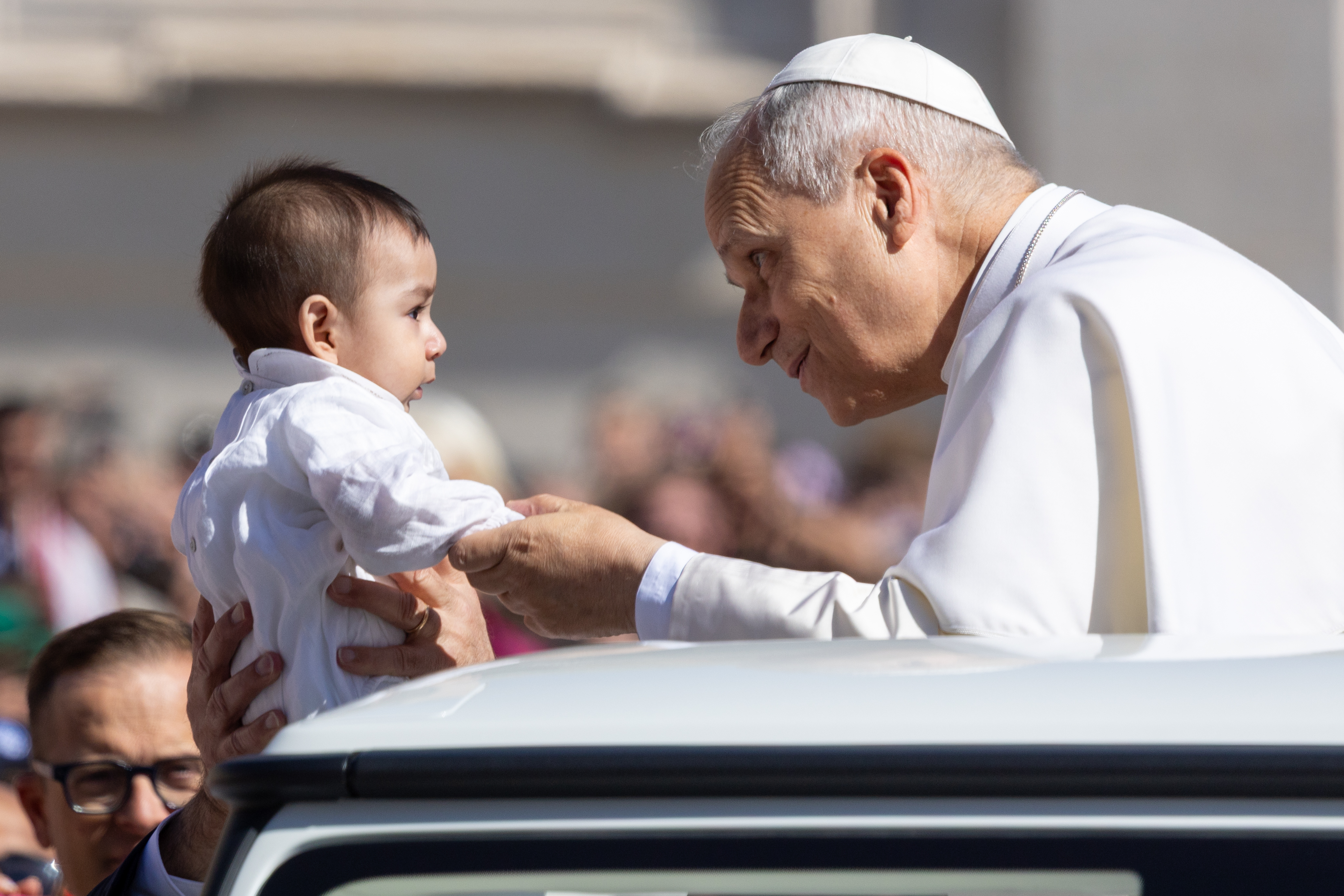 Pope Leo XIV stoops to greet a baby while circling St. Peter’s Square in the popemobile before his general audience on Wednesday, May 20, 2026. | Credit: Daniel Ibanez/EWTN News