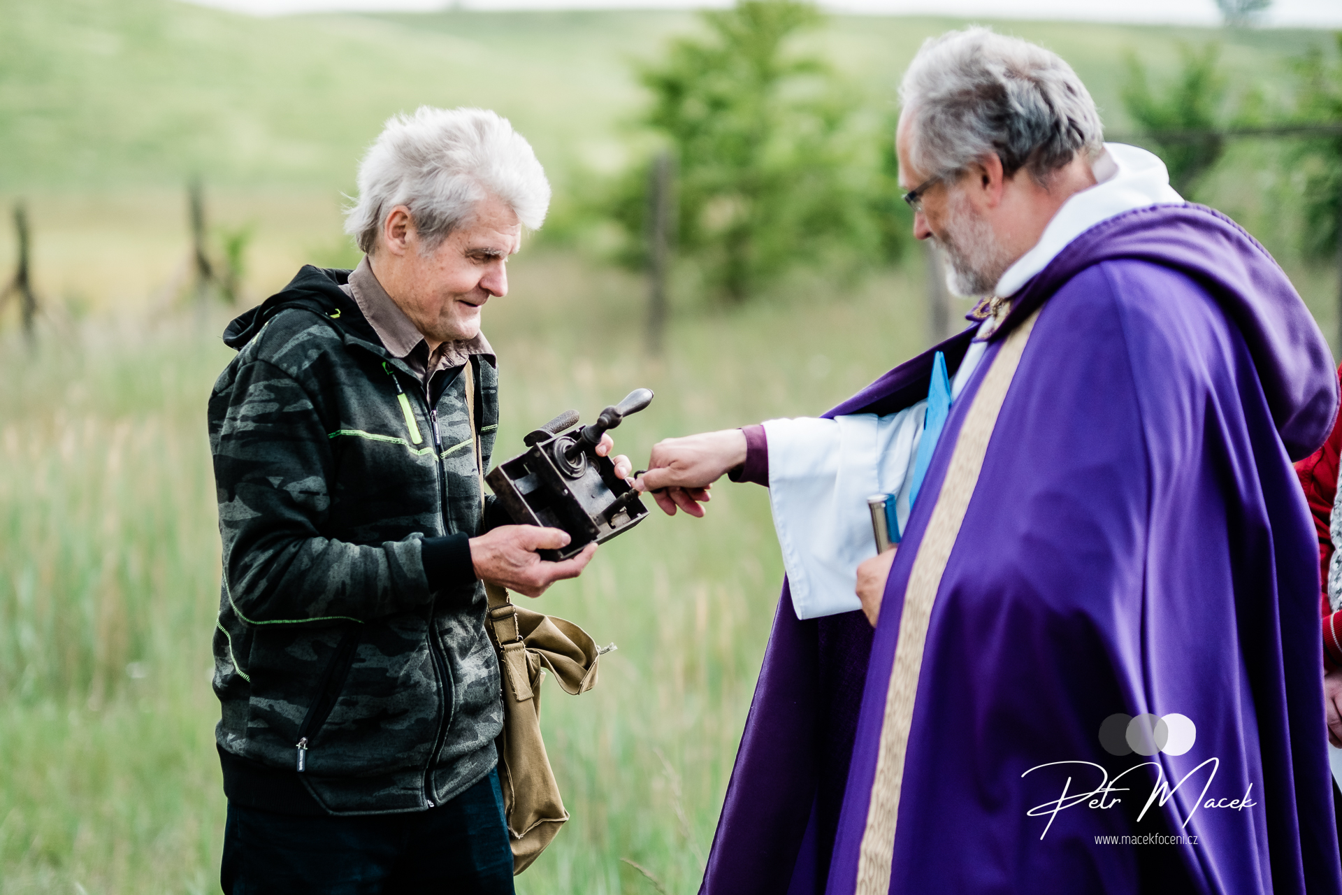 A man presents a preserved artifact from the demolished Church of All Saints to a priest during a gathering of former parishioners above the buried village of Radovesice in the Czech Republic in 2023. | Credit: Petr Macek
