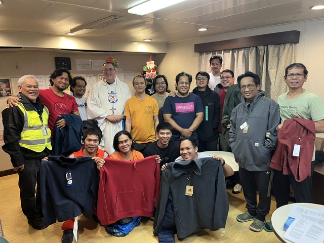 Seattle Auxiliary Bishop Frank Schuster gathers with Filipino crew members who were gifted new jackets by Stella Maris after celebrating an early Christmas Mass on board their ship in December 2025. | Credit: Photo courtesy of Bishop Frank Schuster