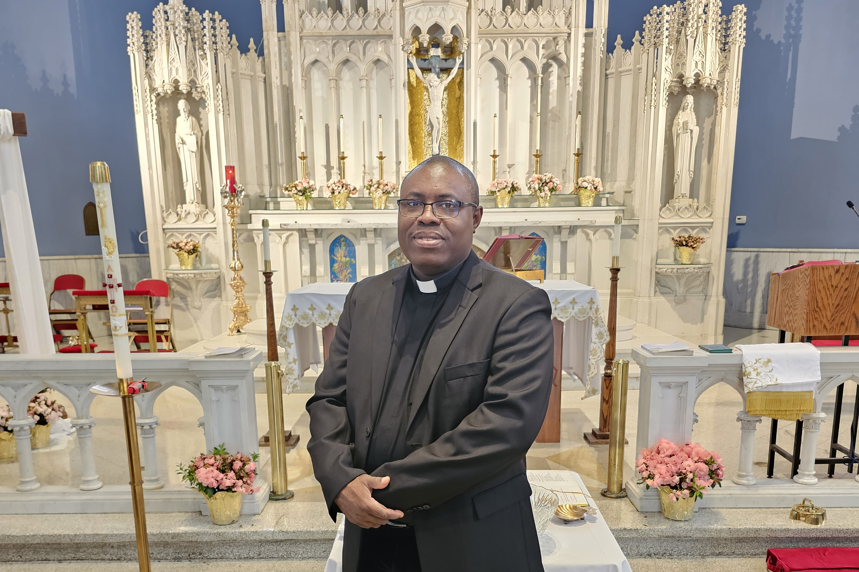 Father Mark Thomas Ameh in front of the high altar of Sts. Martha, Mary, and Lazarus Parish in Chicago. | Credit: Photo courtesy of Father Mark Thomas Ameh