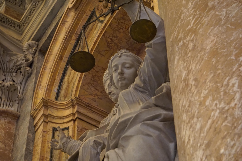 Detailed close-up of a Renaissance marble statue depicting Lady Justice, the ancient Roman goddess Justitia, with scales inside St. Peter’s Basilica at the Vatican. | Credit: Alexander Ruszczynski/Shutterstock