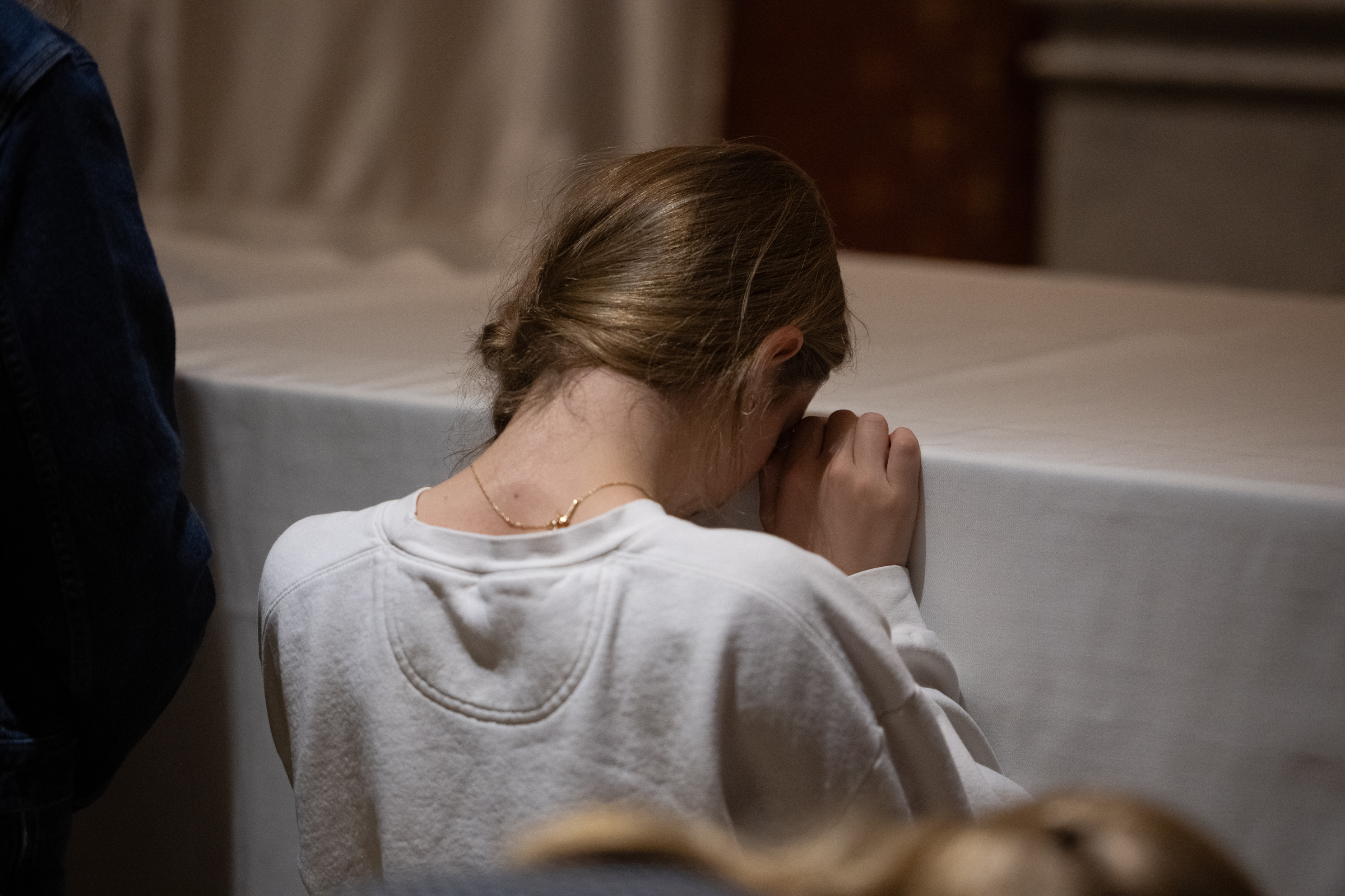 A young woman prays with her hands clasped near the covered tomb of Archbishop Fulton J. Sheen in
the cathedral at Peoria, Illiniois. The visit took place on Sept. 23, 2026, the eve of Venerable Archbishop
Fulton J. Sheenʼs beatification in St. Louis. | Credit: Jeffrey Bruno
