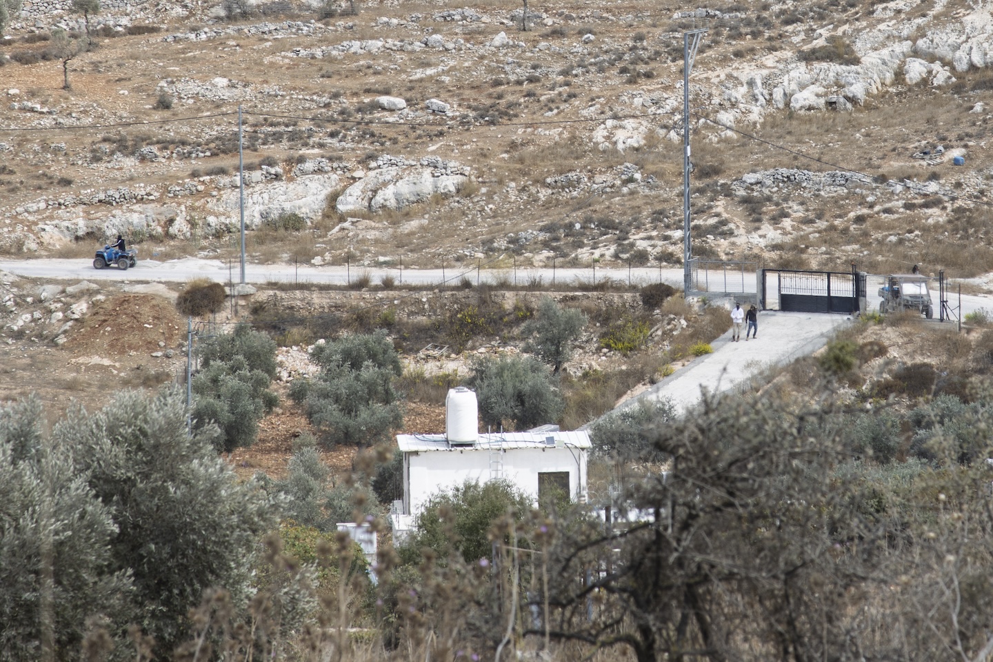 Settlers prepare to enter a resident’s home in Taybeh. Repeated attacks and vandalism have prevented the owner from moving in, even seven years after its construction. | Credit: Sanad Sahelia